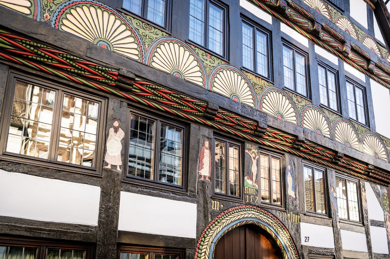 Nahaufnahme der Verzierungen am Adam und Eva Haus. Dargestellt wird die Kreuzigungsgruppe, die Verkündigungsszene sowie die Christusfigur. Von rechts nach links gelesen wird die christliche Heilslehre von der Erbsünde bis zur Erlösung beschrieben.