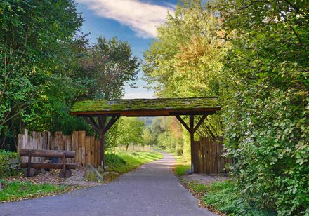 Landwehrtor aus Holz mit Bewuchs rechts und links des Weges